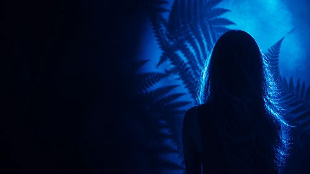 Hairy Pussy OnlyFans creators — long flowing hair catching bright blue rim light, layered fern shadows across the wall