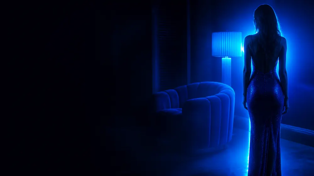 Ssbbw OnlyFans creators — woman in a fitted evening dress in neon rim light, a plush oversized armchair by the lamp