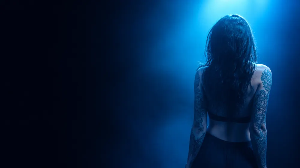Tattooed OnlyFans creators — woman posing under glowing softbox studio lights, inked sleeve patterns catching the studio light